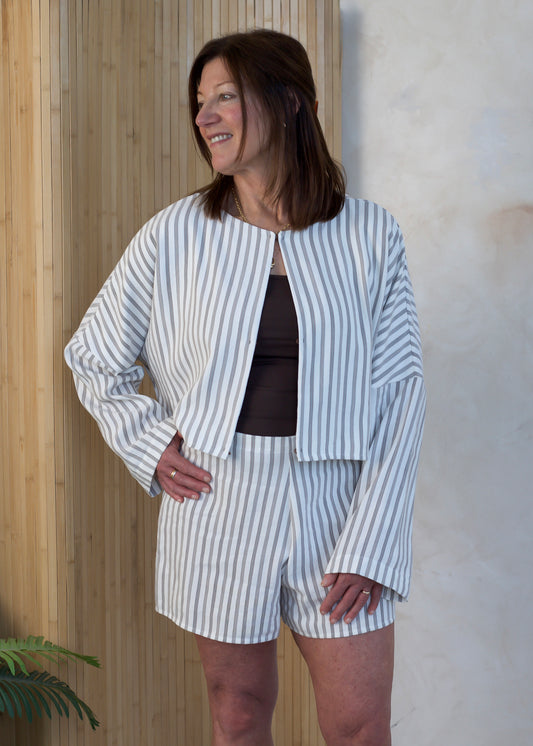 Woman wearing a striped outfit standing against a wooden wall.