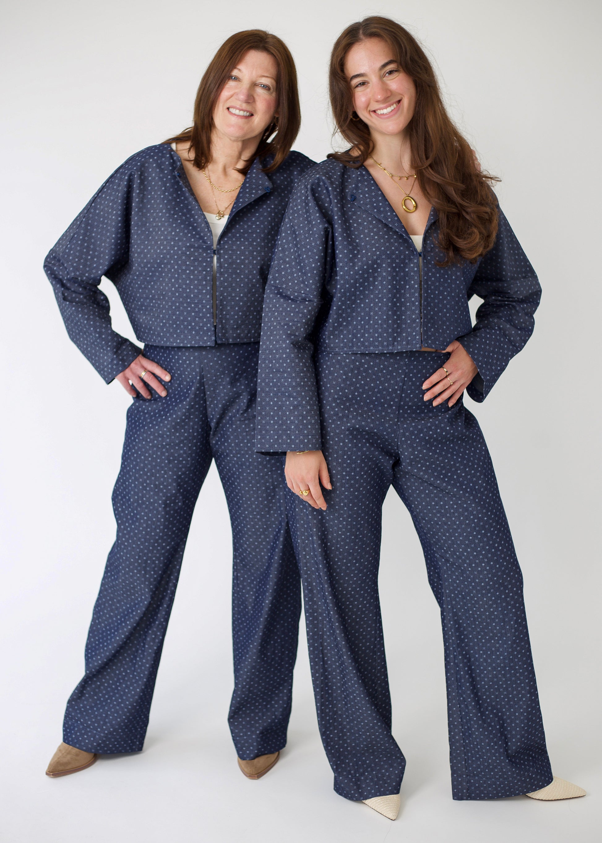 Two women wearing matching blue polka dot outfits on a white background