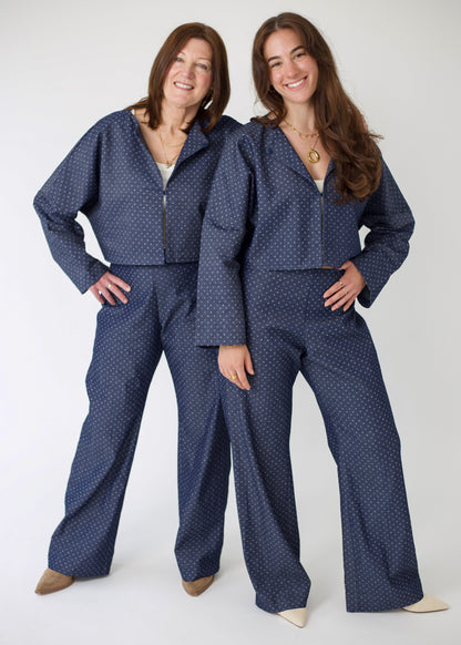 Two women wearing matching blue polka dot outfits on a white background