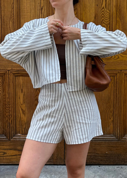 Woman wearing a matching striped outfit with a brown bag against a wooden background