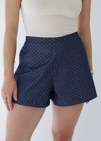 Person wearing navy blue polka dot shorts on a plain background