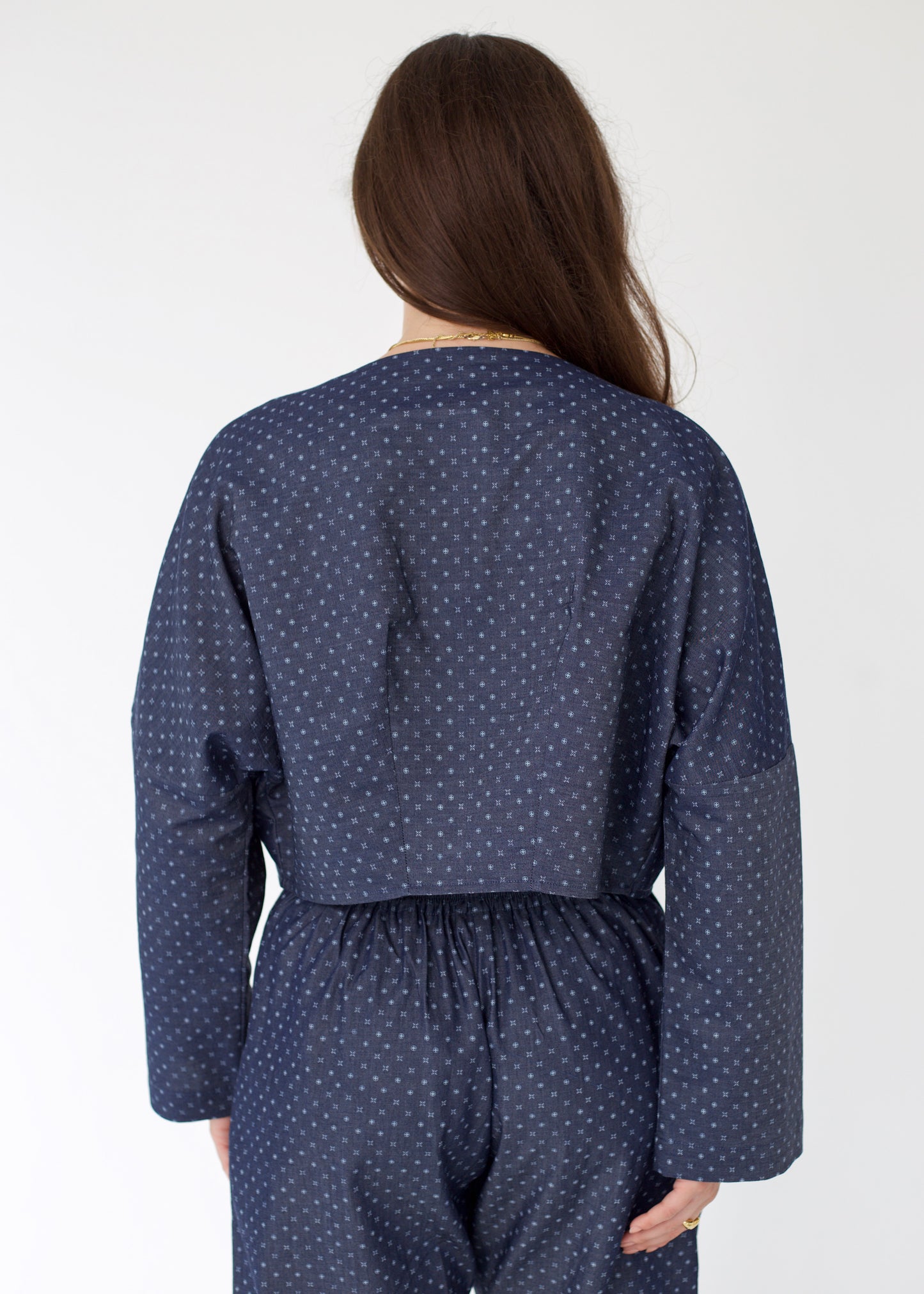 Person wearing a navy blue polka dot outfit on a white background