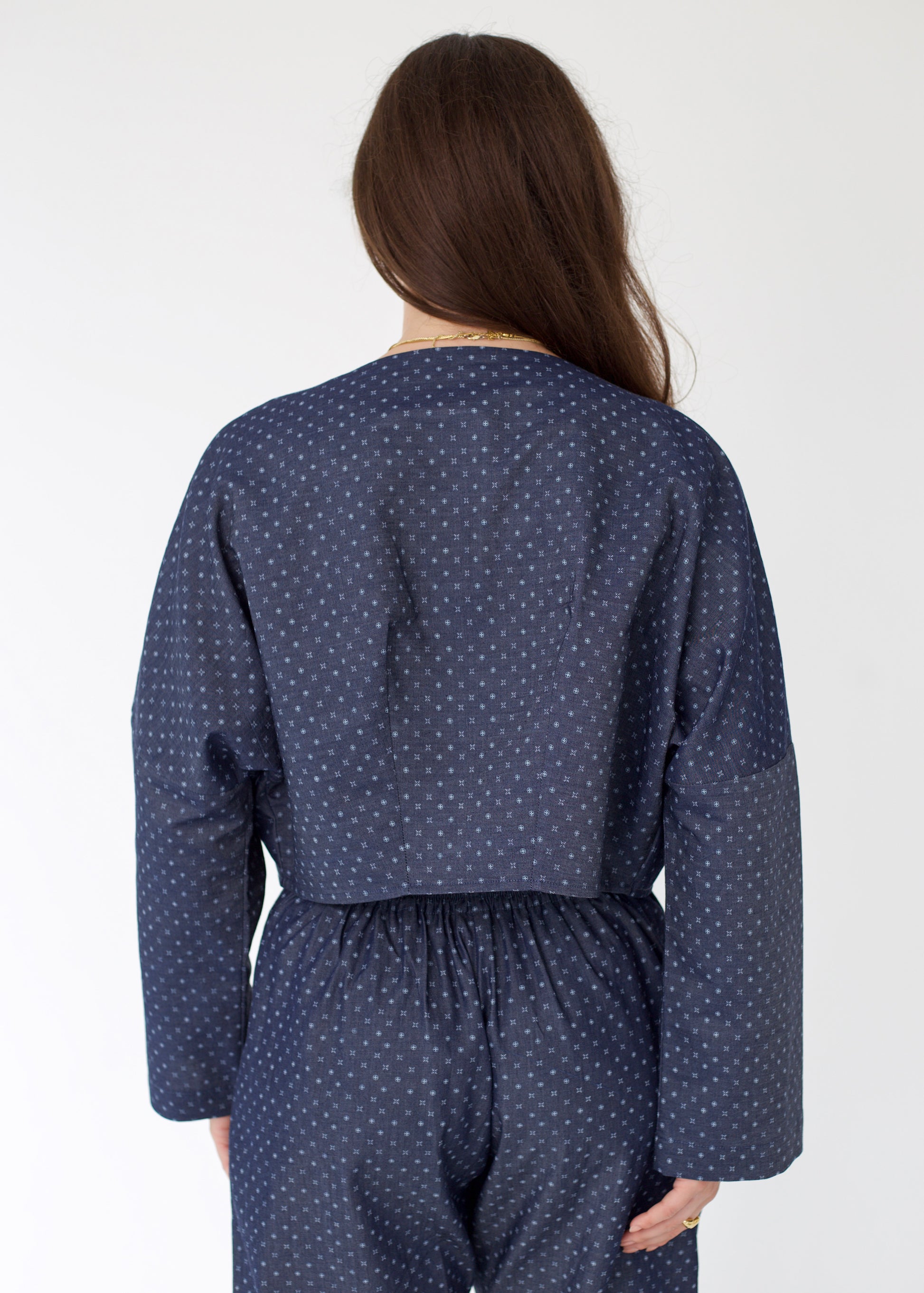 Person wearing a navy blue polka dot outfit on a white background