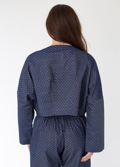 Person wearing a navy blue polka dot outfit on a white background