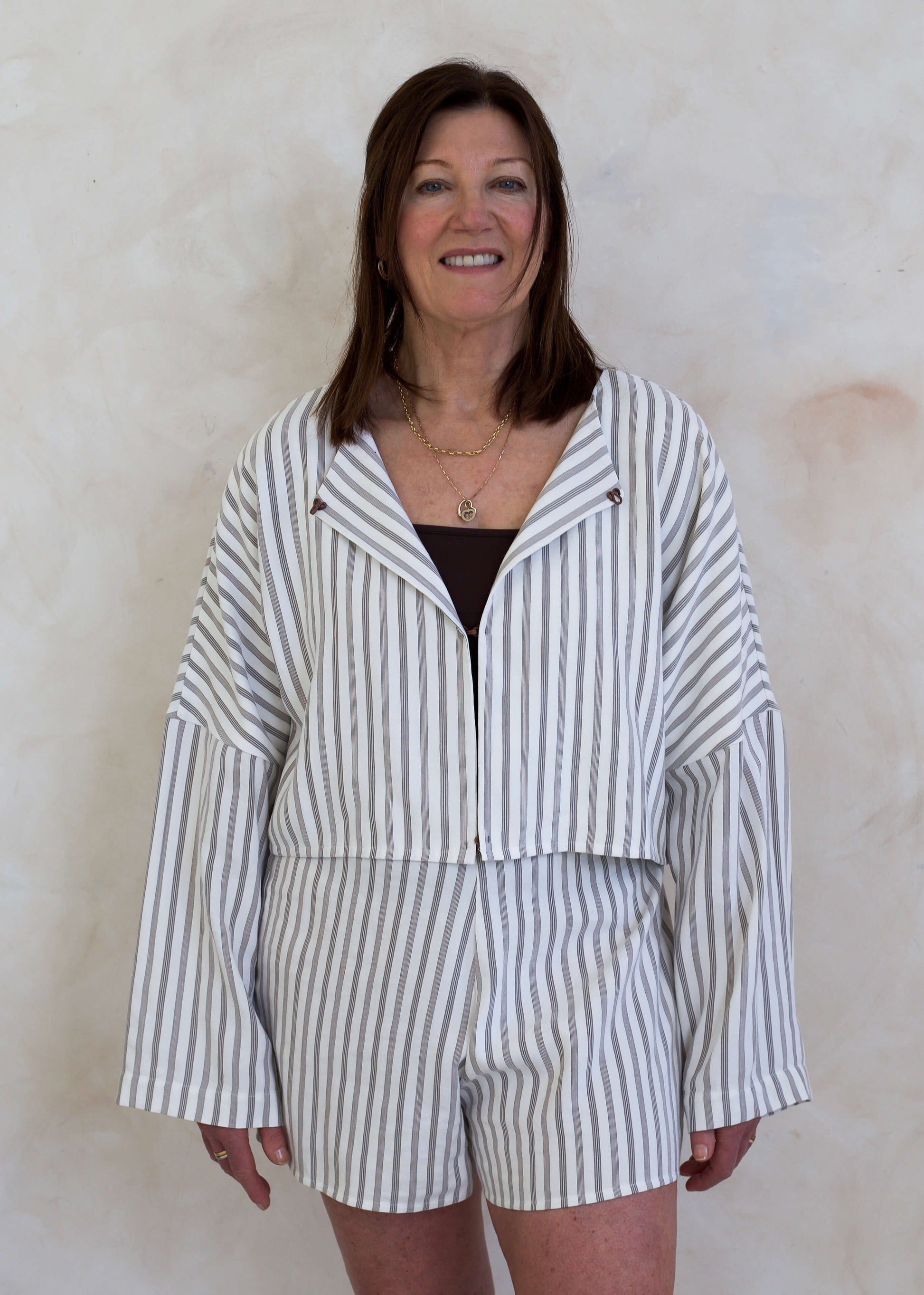 Woman wearing a striped outfit against a plain background